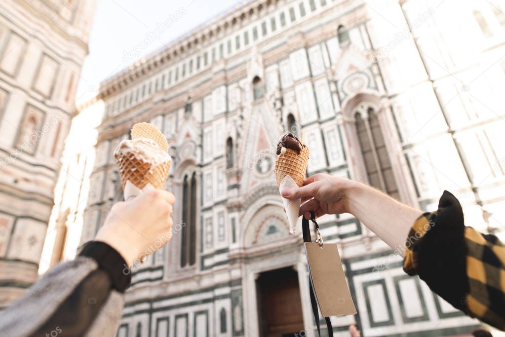 Hands hold the traditional Italian gelato ice cream. Couple holding ice cream gelato on background Cattedrale di Santa Maria del Fiore, Florence, Italy