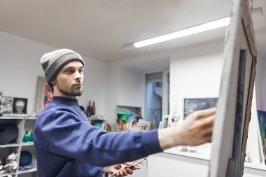 Bir resim bir stüdyoda bir tuval üzerine resmi bir genç öğrenci ressamın portresi. Sanat okulu öğrencisi bir resim çizer. Boyama kavramı.