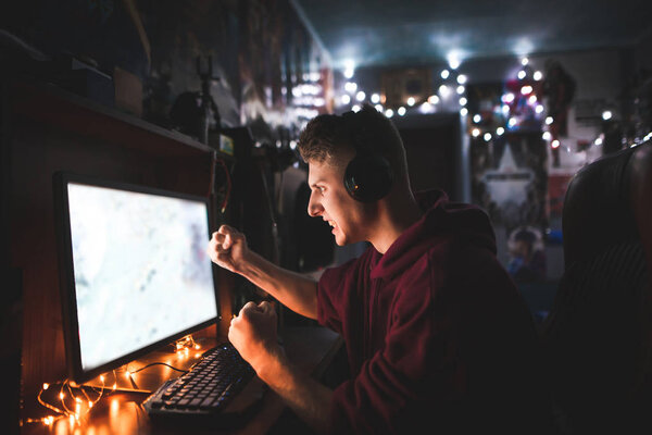 Злой подросток-геймер играет в видеоигры дома на компьютере, сердито глядя на экран. Эмоциональный геймер играет в видеоигры дома в уютной комнате
.
