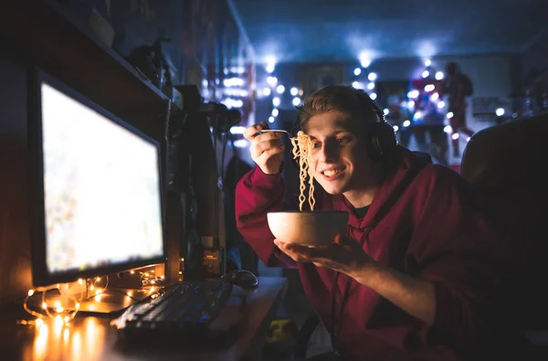 Happy Young Man Uses Computer Home Eats Noodles Gamer Plays — Stock Photo, Image