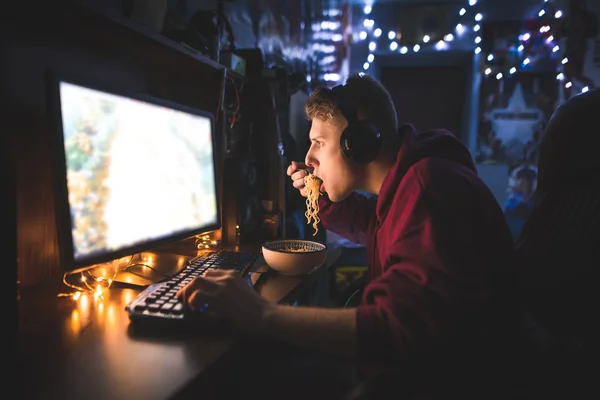 Портрет Сфокусированного Геймера Играющего Дома Видеоигры Компьютере Поедающего Суп Лапшой — стоковое фото
