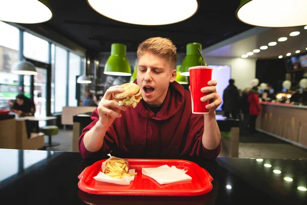 Śmieszne Młody Mężczyzna Siedzi Restauracji Fast Food Burger Szkła Jego — Zdjęcie stockowe