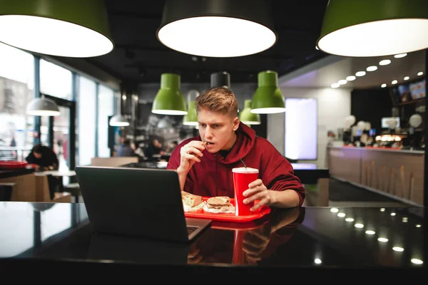 Retrato Joven Comiendo Comida Rápida Restaurante Usando Portátil Freelancer Concentrado — Foto de Stock