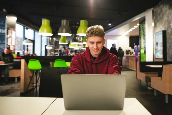 Ragazzo Sorridente Siede Fast Food Guarda Schermo Del Portatile Sorride — Foto Stock