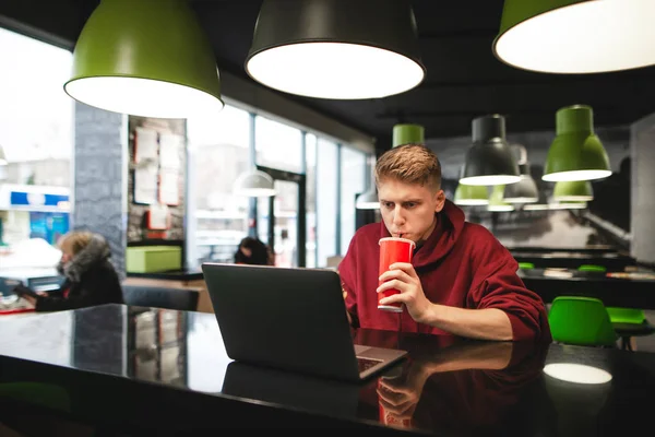 Серьезный Молодой Человек Сидит Столом Кафе Пьет Стекла Смотрит Ноутбук — стоковое фото