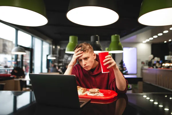 Atractivo Joven Platos Comida Rápida Restaurante Utiliza Ordenador Portátil Estudiante —  Fotos de Stock