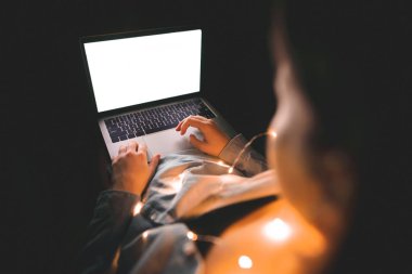 Kız ışık cesette yangınlar, geceleri yatakta yatıyor ve bir dizüstü bilgisayar kullanarak. Bir lamba atmosferde evde çalışma. Kadın ve laptop ile beyaz perde, boşaltmak. Kız gece bir dizüstü bilgisayarda internet kullanır