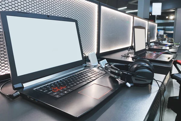 Gaming laptops and headphones in the electronics store. Purchasing equipment for professional gaming in the technology store, cyberport concept. Computer club. Table with gaming laptops.