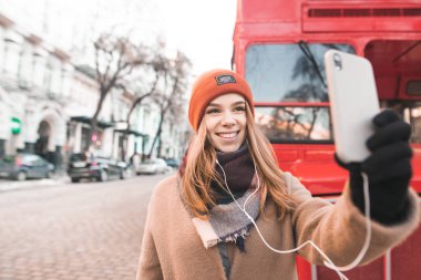 Rahat bir ekose bir fincan kahve onun elinde ile kaplı bir gülümseyen kız portresi bir kafede oturur ve kameraya benziyor. bir kafede kahve içme masada oturan ute kız