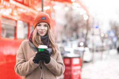 Rahat bir ekose bir fincan kahve onun elinde ile kaplı bir gülümseyen kız portresi bir kafede oturur ve kameraya benziyor. bir kafede kahve içme masada oturan ute kız