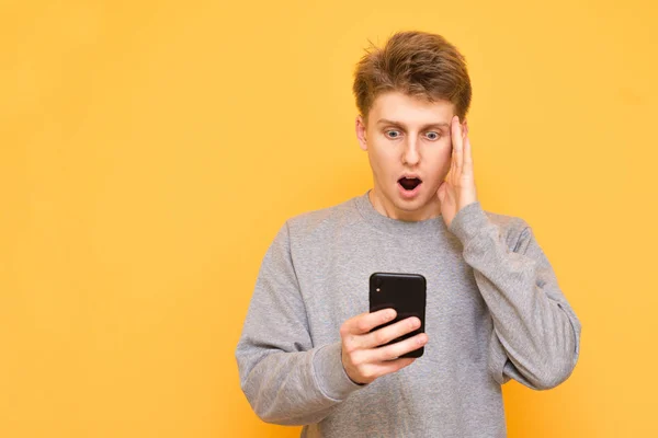 Portrait Shocked Guy Standing Smartphone His Hand Yellow Background Looking — Stock Photo, Image
