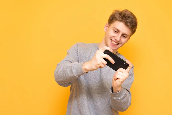 Portrait Smiling Young Man Playing Mobile Games Smartphone Isolated Yellow — Stock Photo, Image