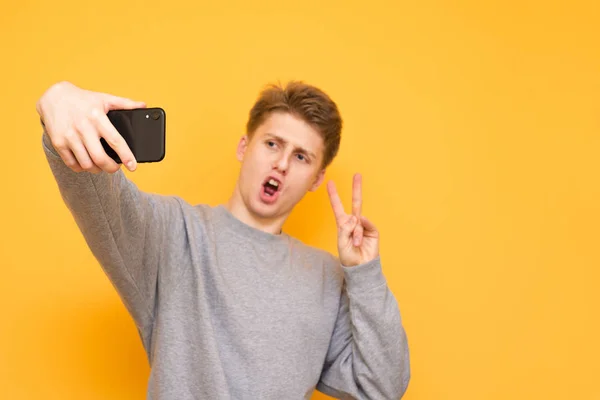 Attractive Young Man Stands Yellow Background Poses Smartphone Camera Guy — Stock Photo, Image