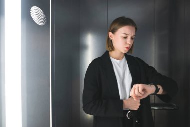 Bu Asansör geç ediliyor endişeli kadın. İşkadını zaman kontrol onun saatine bakıyor. Çalışan bir şeyin peşinde.