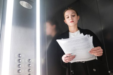 Modern iş kadını asansöre gazetelerde okuyor. Kadın işçilerin Asansör belgelerin incelenmesi.