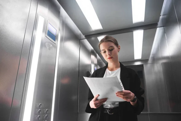 Genç Işkadını Asansörde Belgeleri Okuma Üzerinde Yoğunlaşmıştır Şçisi Kadın Ofis — Stok fotoğraf