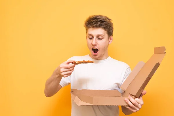 Hungry Guy Pizza His Hands Isolated Yellow Background Emotional Young — Stock Photo, Image