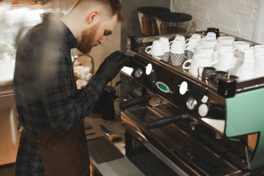 Konsantre barista kahve makinesi kahve hazırlanıyor. Sakallı Kafe sahibi bir kafede içki lezzetli kahve yapmaya odaklanmış.