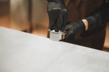 Bir kahve dükkanında çalışan Barista kurcalamak kullanarak barista presler çekilmiş kahve ile kapatın. Barista kahve kavramı yapma kahve dükkanında. Fotoğraf, bir portafilter odaklanmak kapatın.