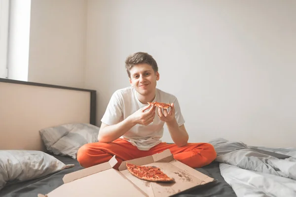 Retrato Joven Feliz Sentado Una Cama Pizza Caja Sosteniendo Pedazo — Foto de Stock