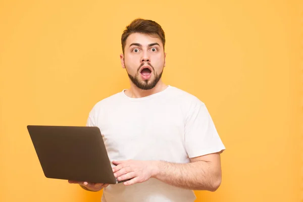 Emocional hombre sorprendido mantiene el portátil en sus manos, mirando i —  Fotos de Stock