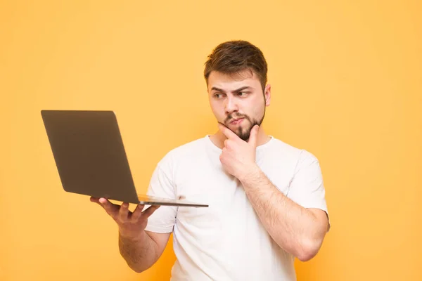 Thoughtful man with a beard dressed in a white T-shirt stands on — Stock Photo, Image