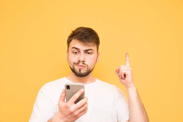 Hombre emocional con barba sostiene un teléfono inteligente en sus manos, mostrar — Foto de Stock