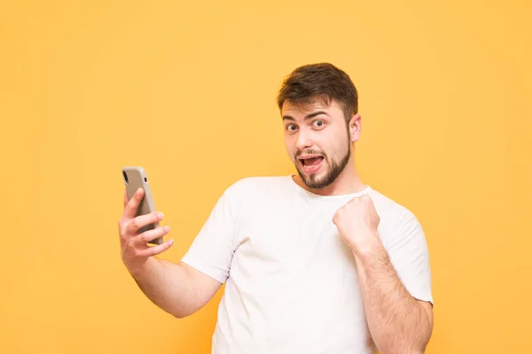 Man has won, holds in the hands of a smartphone looking into the — Stock Photo, Image
