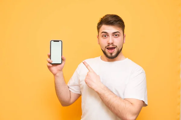 Emotional man with a beard,wearing a white T-shirt holds a smart — Stock Photo, Image