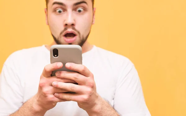 Foto di primo piano, uomo scioccato guardando uno smartphone. Uomo stupito Fotografia Stock