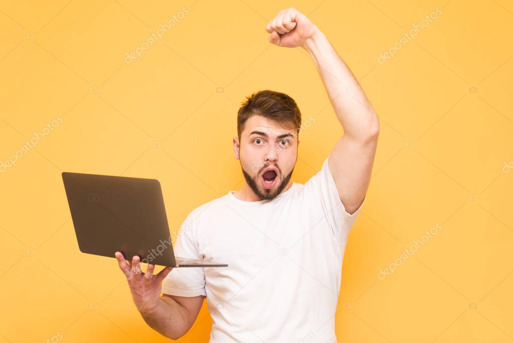 Adult man with a laptop in his hands won, rejoices in victory wi