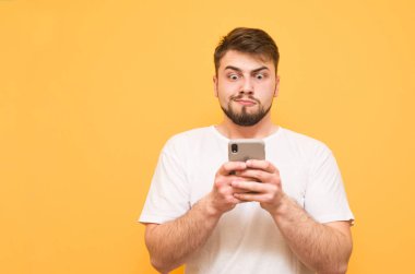 Komik adam sakallı bir smartphone üzerinde sarı bir arka plan kullanır.,