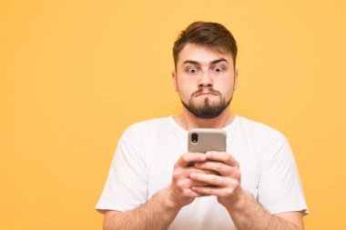 Bir beyaz T-shirt kullanma smartphone ve üzgün bak komik adam giymiş