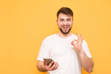 Bir akıllı holding beyaz bir T-shirt giyen mutlu bir adam portresi