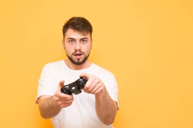 Focused bearded man in a white T-shirt plays a video game on a g clipart