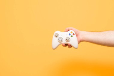Erkek el video oyunları için bir joystick üzerinde sarı bir adam tutar.