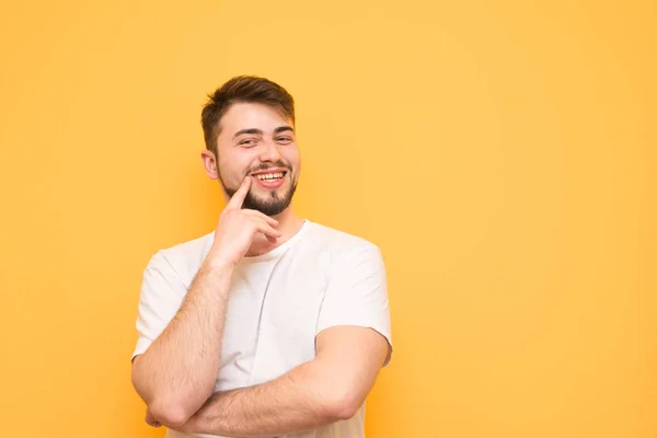 Hombre feliz con barba lleva una camiseta blanca, se para en un amarillo — Foto de Stock