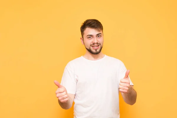 Un hombre barbudo sonriente lleva una camiseta blanca, muestra un pulgar hacia arriba un — Foto de Stock