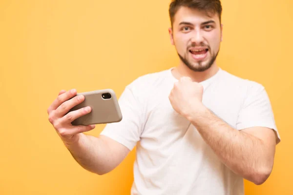 Joyful bearded man holds the smartphone in his hands and rejoice — Stock Photo, Image