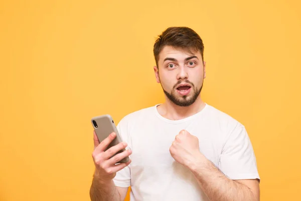 Emotional man with a beard, wearing a white T-shirt, stands on a — Stock Photo, Image