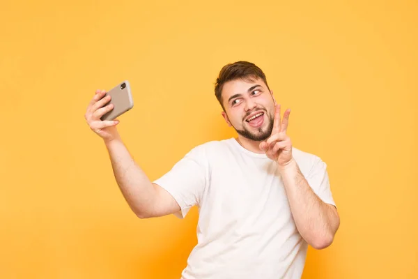 Funny bearded man in a white T-shirt takes selfie on a yellow ba — Stock Photo, Image