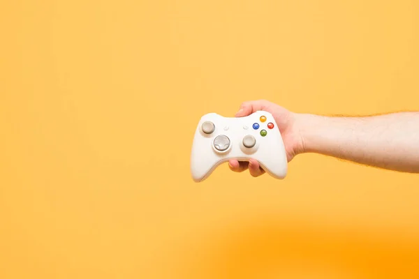 Męskie ręce trzyma joystick do gier wideo na żółtym tle — Zdjęcie stockowe