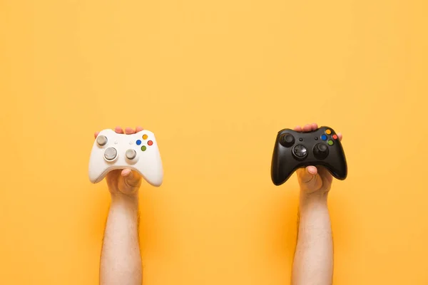 Ellerini iki gamepads beyaz ve siyah sarı bir arka plan üzerinde tutun. — Stok fotoğraf