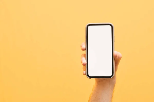 Männliche Hand hält ein modernes Smartphone mit einem weißen, leeren Bildschirm o — Stockfoto