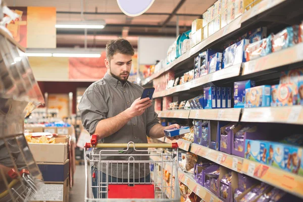 Porträt eines Mannes, der mit einem Einkaufswagen in der süßen Abteilung steht — Stockfoto