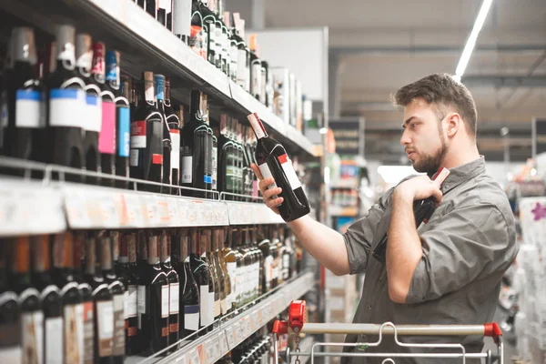 This should be fine. Side view of handsome young man holding bot — Stock Photo, Image