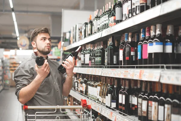 Käufer mit Einkaufswagen steht in der Alkoholabteilung des Supermarktes — Stockfoto