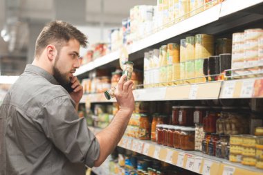 Bir adamın portresi, bir marketteki Konserve sebzeleri seçer, cep telefonu arar. Süpermarket alıcı yiyecek alır. Konserve sebze bölümünün koridorunda duran adam ve ürünleri seçer