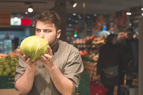 Молодой человек покупает овощи в супермаркете — стоковое фото
