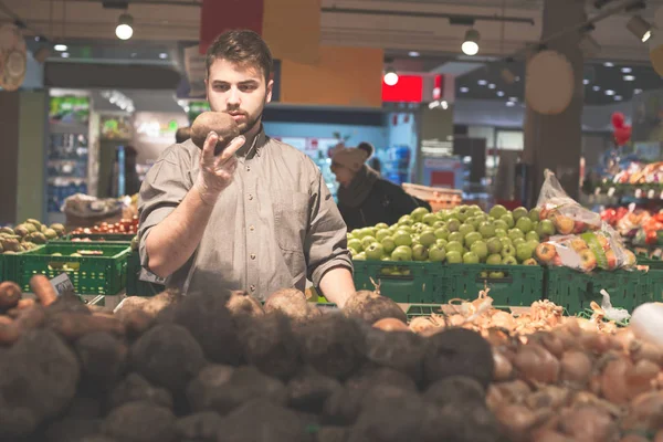Улыбающийся человек держит кучу свеклы в супермаркете — стоковое фото